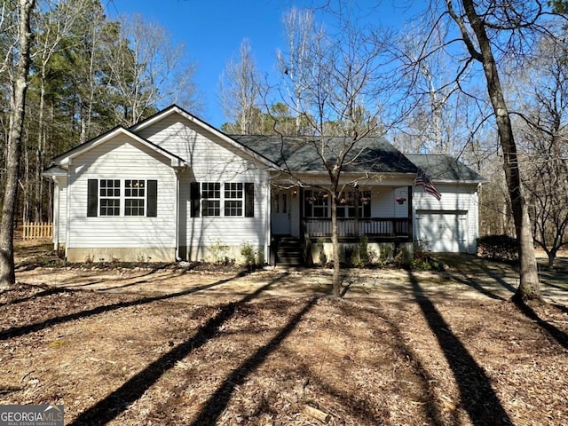 view of front of property featuring a porch, an attached garage, and dirt driveway