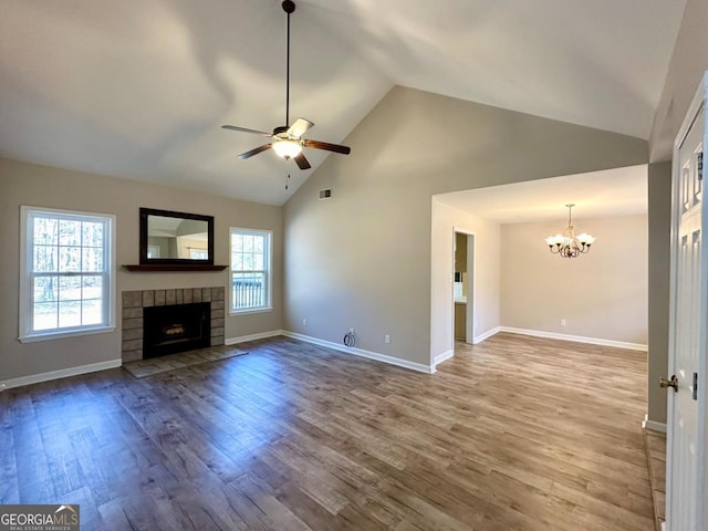 unfurnished living room featuring visible vents, a fireplace with flush hearth, wood finished floors, baseboards, and ceiling fan with notable chandelier