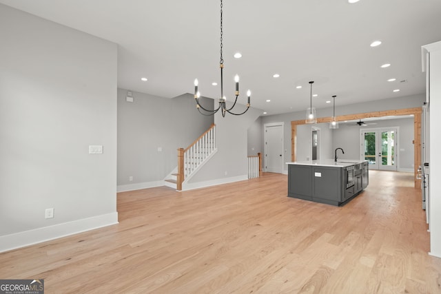 kitchen with baseboards, light countertops, light wood-type flooring, a sink, and recessed lighting