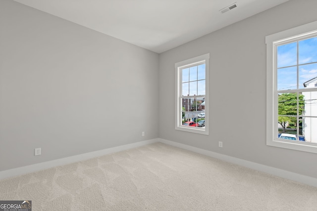 spare room featuring a wealth of natural light, baseboards, visible vents, and carpet flooring