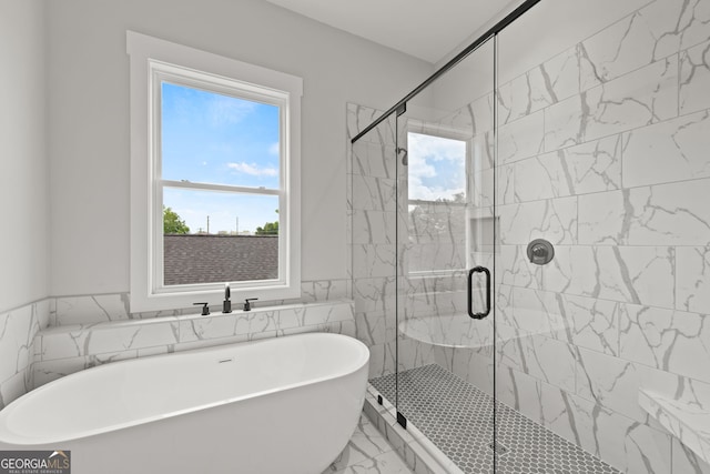 bathroom with marble finish floor, a wainscoted wall, tile walls, a freestanding bath, and a shower stall