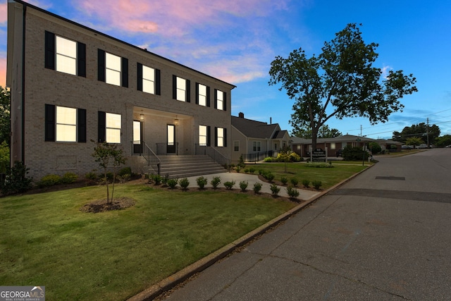 view of front of house with brick siding and a lawn