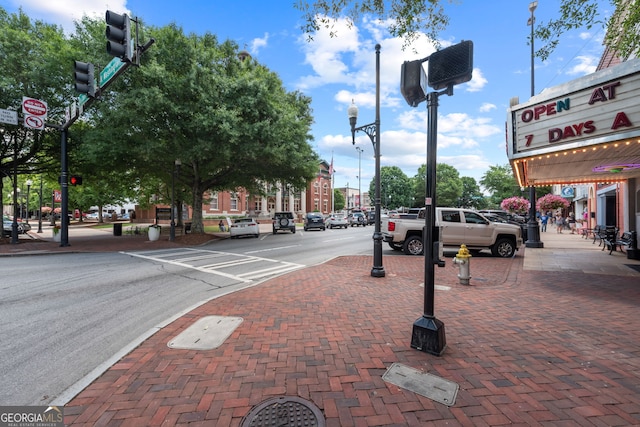 view of road with street lights, traffic lights, and sidewalks