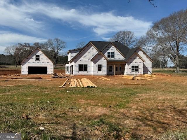 back of property featuring a garage, a yard, and an outbuilding