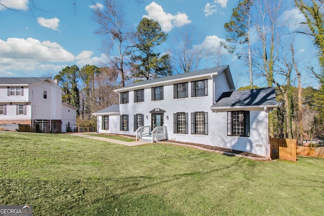 view of front of home featuring a front yard, fence, and brick siding