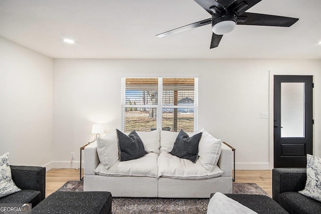 living area with a ceiling fan, light wood-style flooring, and baseboards