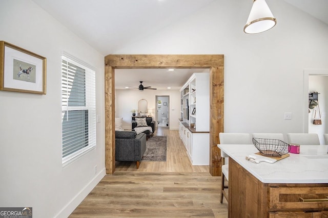 corridor featuring high vaulted ceiling, light wood-type flooring, and baseboards