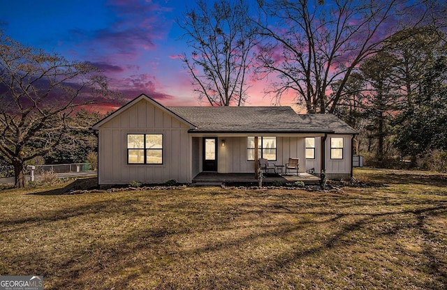 view of front of home with covered porch, a front lawn, board and batten siding, and fence