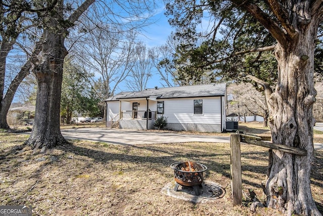 view of front of property featuring central AC, an outdoor fire pit, and concrete driveway