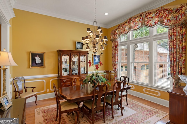 dining room with light wood finished floors, baseboards, ornamental molding, and a notable chandelier