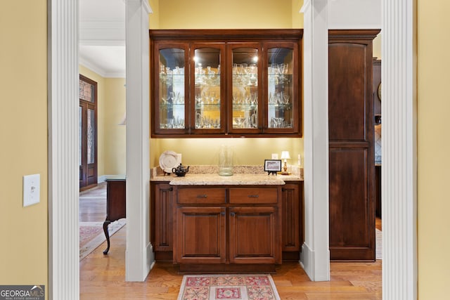 bar with light wood-style flooring, baseboards, and crown molding