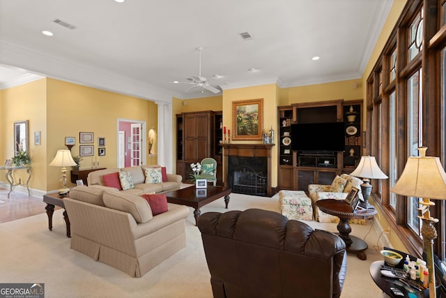 living area with crown molding, a fireplace, decorative columns, and visible vents