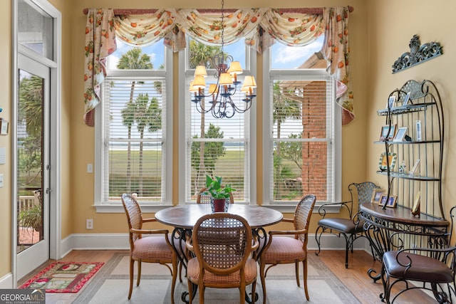 dining space featuring light wood-type flooring, a notable chandelier, and baseboards