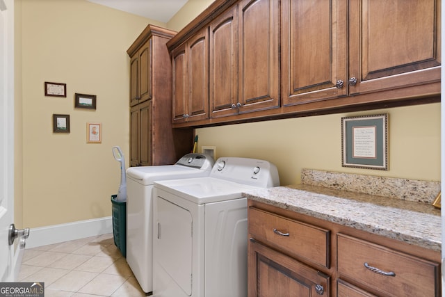 washroom with baseboards, cabinet space, washing machine and clothes dryer, and light tile patterned floors