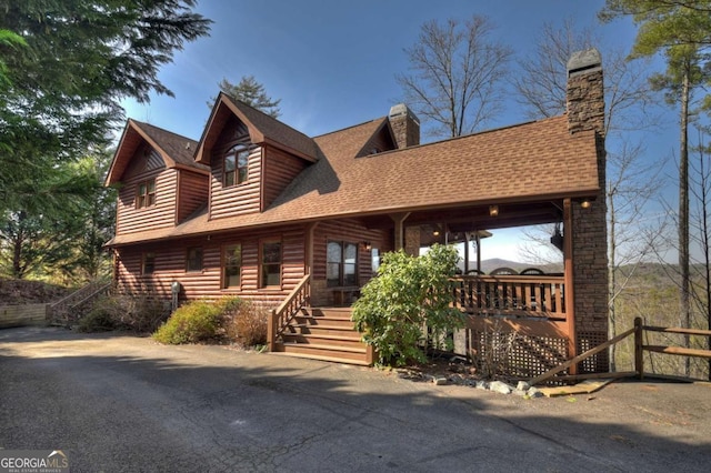 log-style house featuring roof with shingles, stairway, a chimney, and log veneer siding