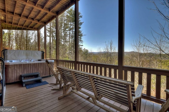 wooden deck featuring a wooded view and a hot tub