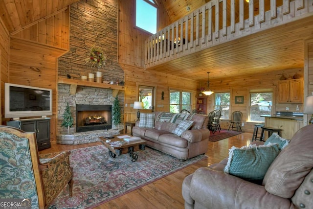 living area with wooden ceiling, a fireplace, wood finished floors, and wood walls