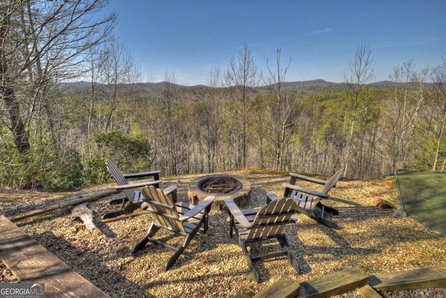 view of yard with an outdoor fire pit and a wooded view