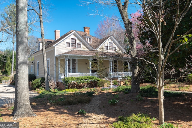 view of front of home featuring a chimney and a porch