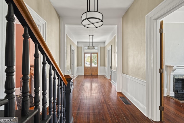 foyer entrance featuring a fireplace, visible vents, stairs, french doors, and dark wood-style floors