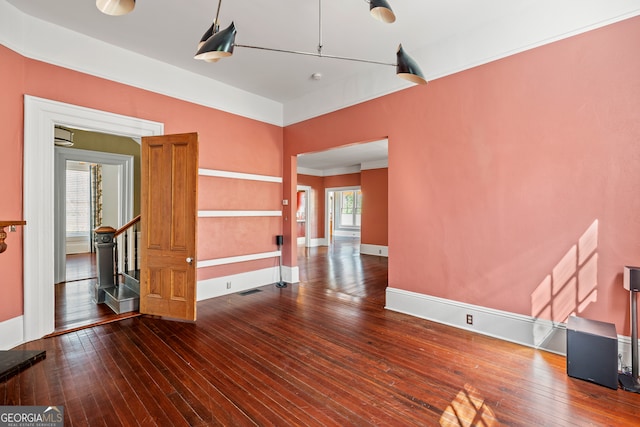 unfurnished room with a wealth of natural light, wood-type flooring, stairway, and baseboards