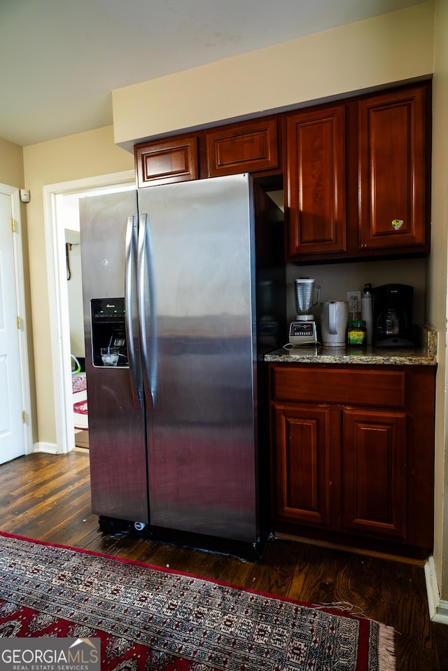 kitchen with dark wood-style flooring, dark brown cabinets, stainless steel refrigerator with ice dispenser, and baseboards