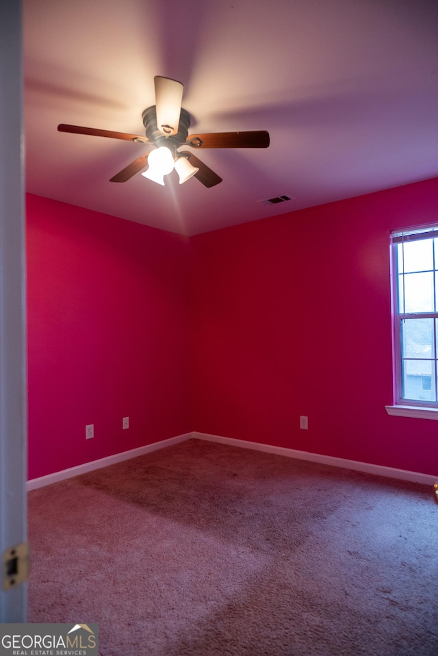 spare room featuring carpet, visible vents, ceiling fan, and baseboards