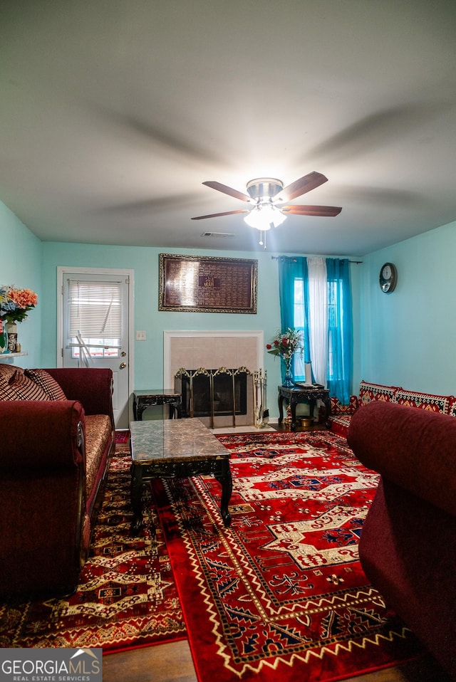 living room with visible vents, ceiling fan, and a tiled fireplace