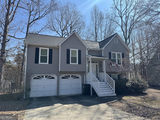 bi-level home featuring a garage, concrete driveway, and roof with shingles