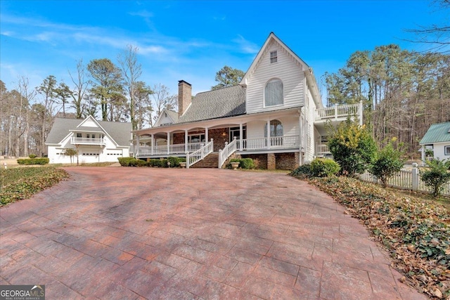 view of front of home with decorative driveway, covered porch, and a chimney