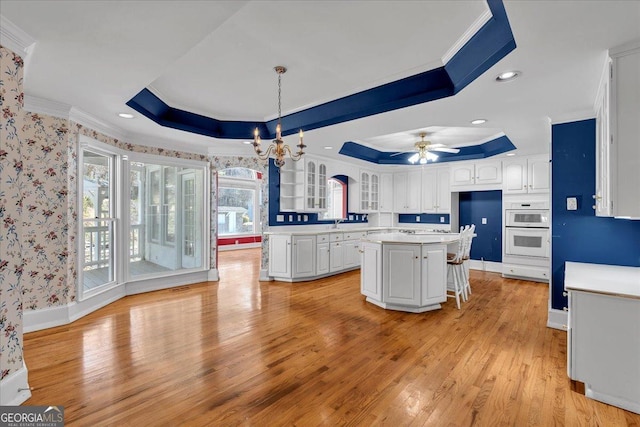 kitchen with a raised ceiling, white cabinetry, and crown molding