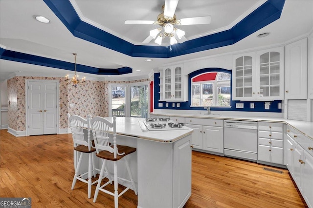 kitchen featuring ornamental molding, a center island, white appliances, and a raised ceiling