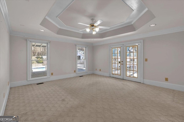 carpeted spare room featuring french doors, a raised ceiling, visible vents, ornamental molding, and baseboards