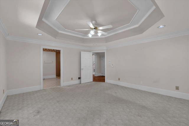 unfurnished bedroom featuring a tray ceiling, carpet, crown molding, ceiling fan, and baseboards