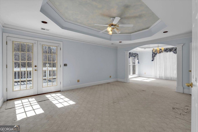 unfurnished room with visible vents, a raised ceiling, arched walkways, and french doors