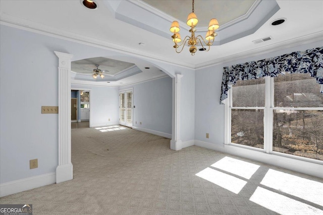 carpeted empty room with arched walkways, visible vents, baseboards, ornamental molding, and a tray ceiling