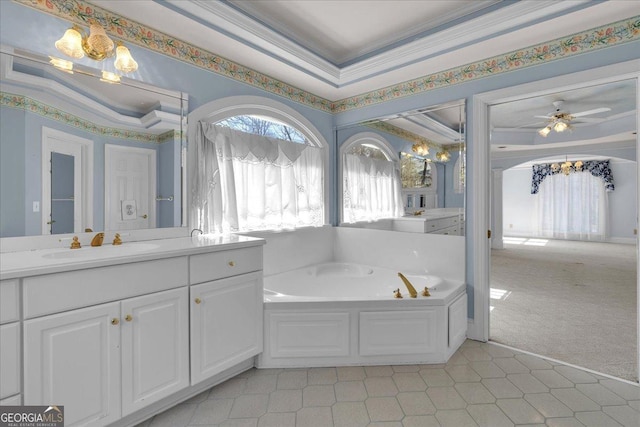 bathroom featuring a garden tub, ornamental molding, a raised ceiling, and vanity