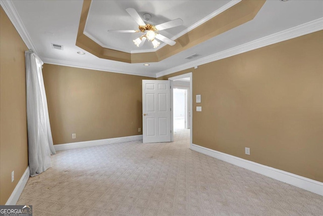 unfurnished bedroom with ornamental molding, a tray ceiling, visible vents, and light colored carpet