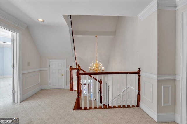 corridor featuring lofted ceiling, ornamental molding, an inviting chandelier, an upstairs landing, and carpet floors