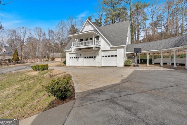 view of side of property with driveway, roof with shingles, and a balcony