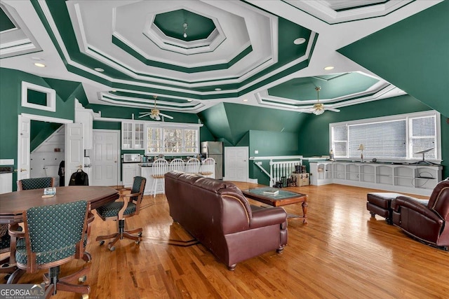 living area featuring crown molding, a raised ceiling, a ceiling fan, and wood finished floors