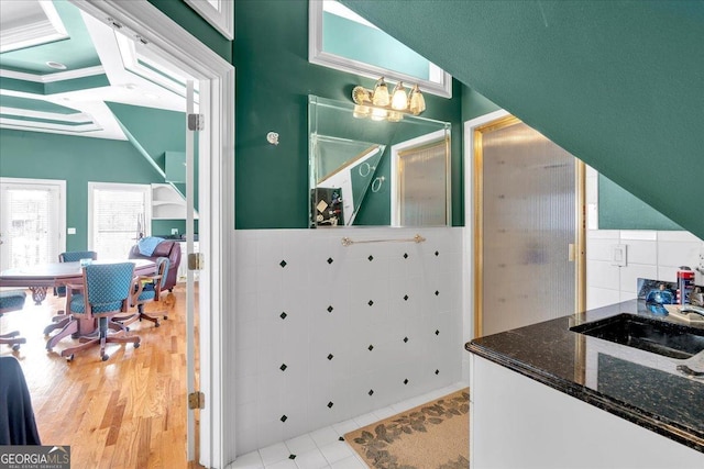 bathroom with wainscoting, tile walls, a sink, and wood finished floors