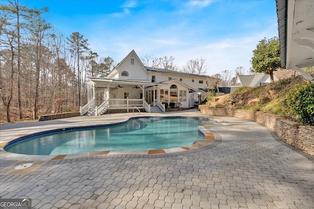 outdoor pool featuring a patio area, ceiling fan, stairs, and a deck