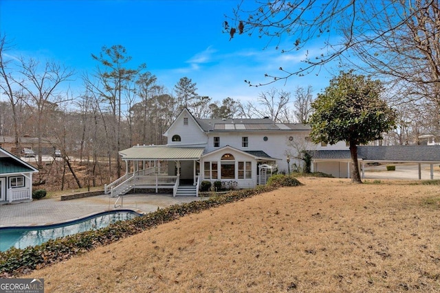 back of property with covered porch, metal roof, and a fenced in pool