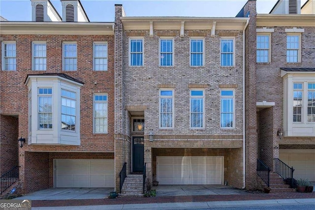 townhome / multi-family property featuring an attached garage, entry steps, and brick siding