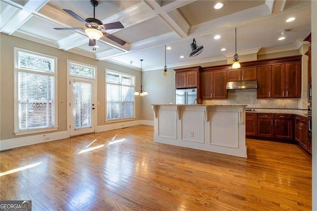 kitchen featuring light wood finished floors, coffered ceiling, decorative backsplash, built in refrigerator, and under cabinet range hood