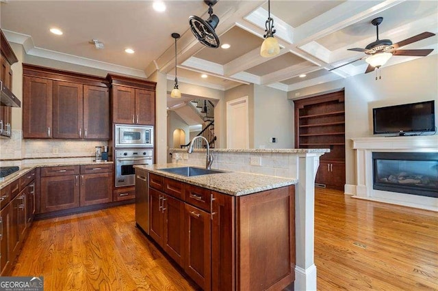 kitchen featuring light stone counters, coffered ceiling, a sink, appliances with stainless steel finishes, and light wood-type flooring