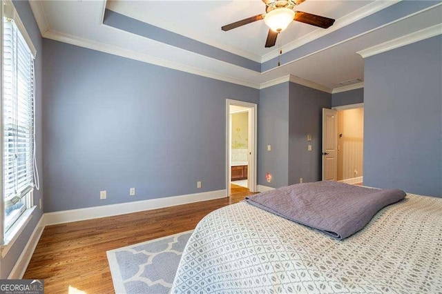 bedroom with baseboards, crown molding, a tray ceiling, and wood finished floors