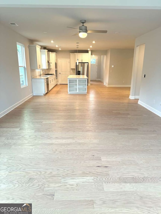 kitchen with light wood-style flooring, stainless steel appliances, visible vents, baseboards, and open floor plan