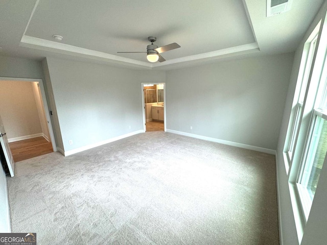 unfurnished bedroom with baseboards, visible vents, a raised ceiling, and carpet flooring